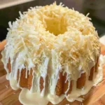 Pineapple Coconut Pound Cake 4 A moist pineapple coconut pound cake topped with coconut glaze and toasted coconut flakes on a white cake stand.