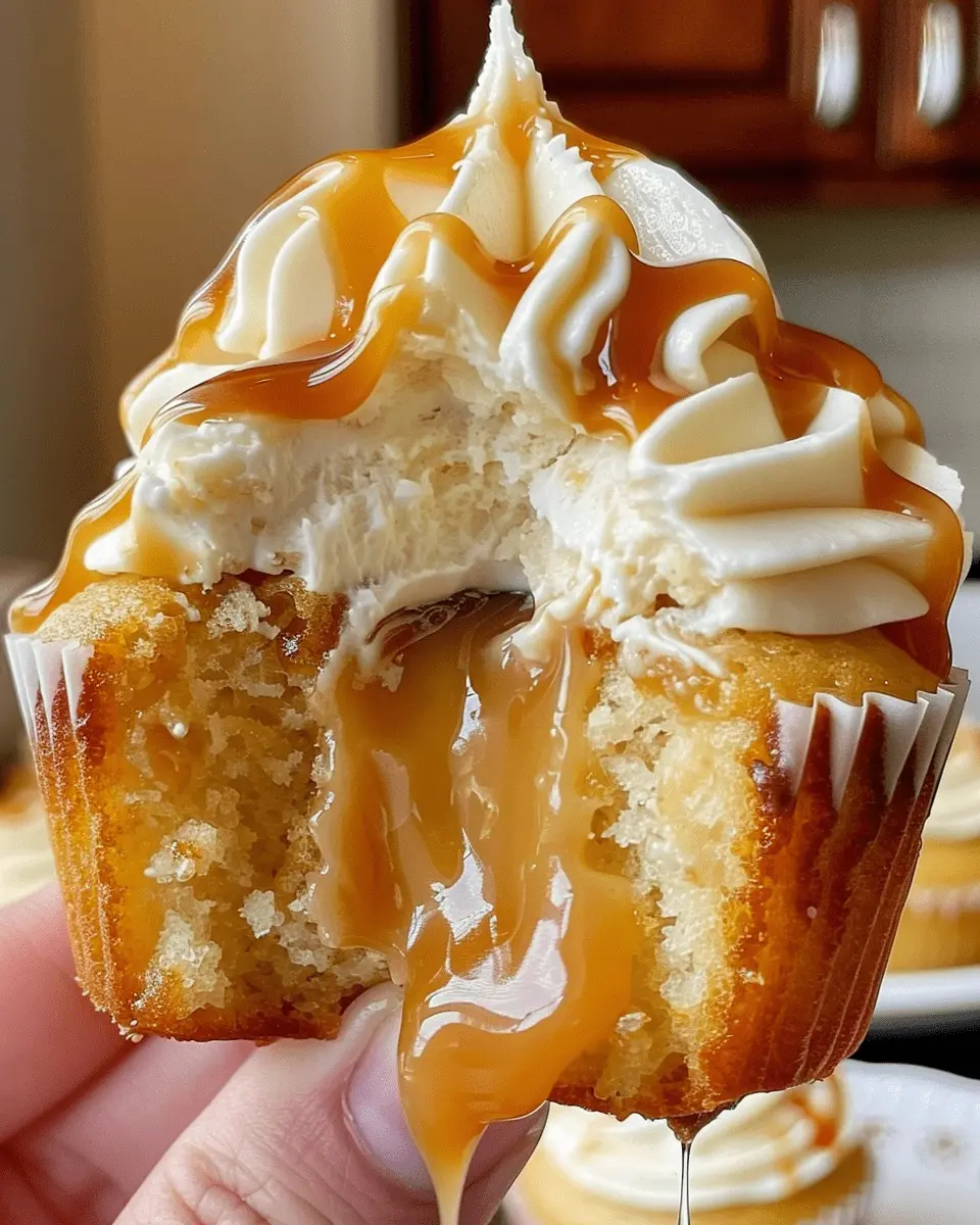 Salted caramel cream cheese cupcakes with gooey caramel filling and creamy frosting, drizzled with salted caramel sauce.