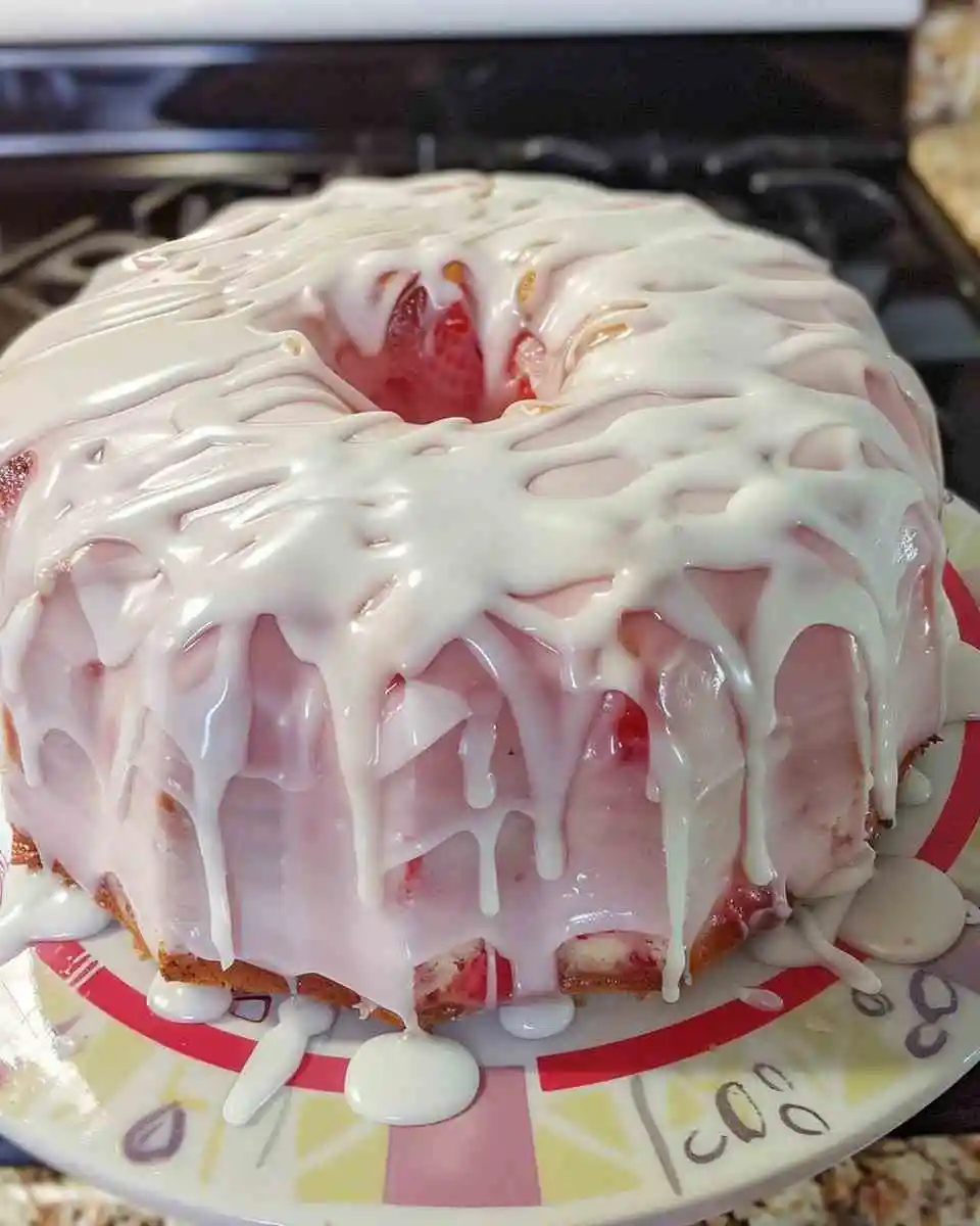 Moist strawberry cream cheese pound cake topped with pink glaze and fresh strawberries