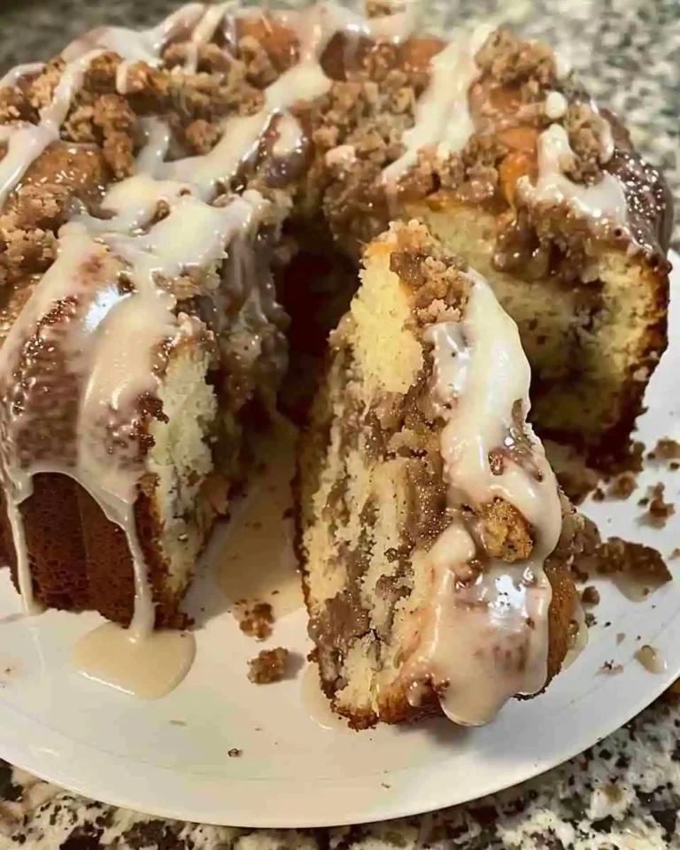 Freshly baked sock it to me pound cake with cinnamon swirl and glaze, served on a white cake stand.