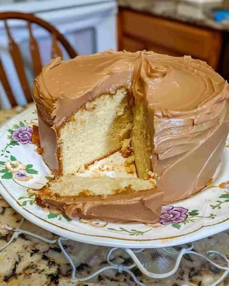Home 16 A rich sour cream pound cake topped with thick caramel frosting, sliced and served on a rustic cake stand.