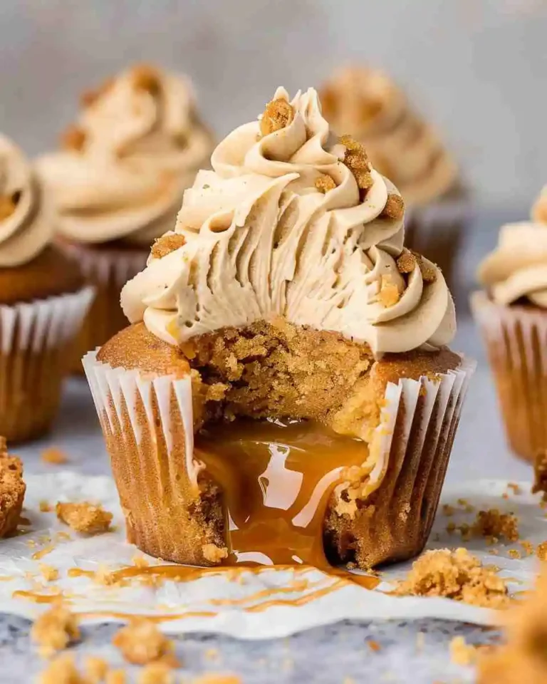Home 17 Freshly baked Biscoff cupcakes with Biscoff buttercream frosting, topped with cookie crumbs and served on a white plate.